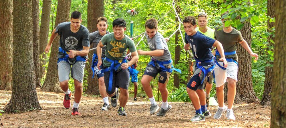 Avon Old Farms students running through woodland.