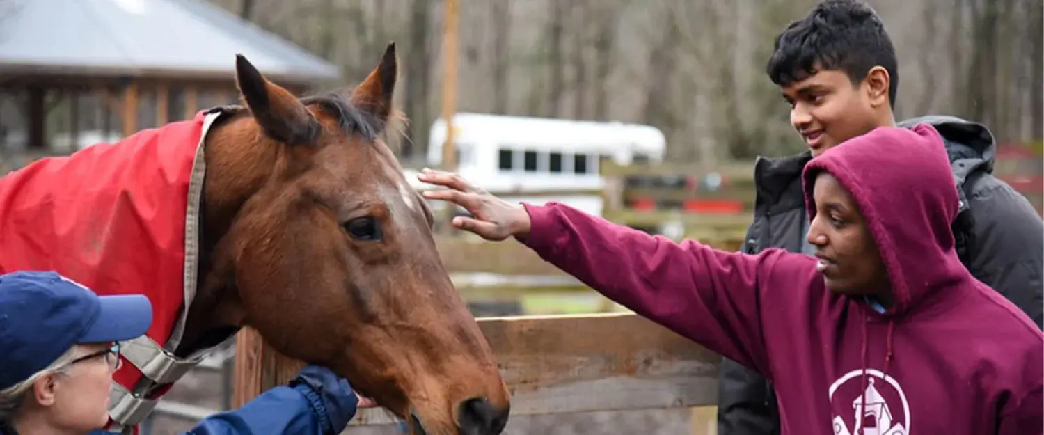 Avon Old Farms students petting a horse in an Intersession activity.