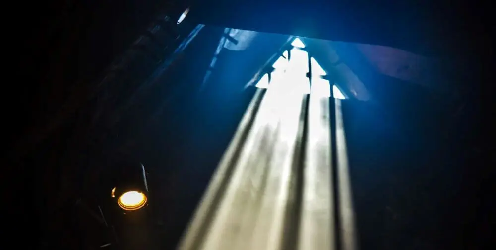 Photograph of rays of light shining through a window in the rafters.