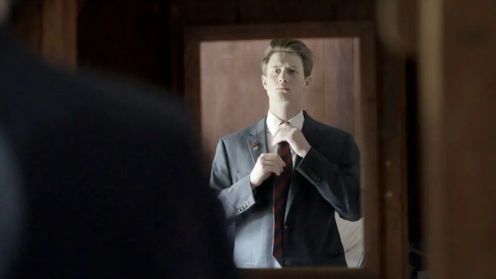 Avon Old Farms student straightening tie.