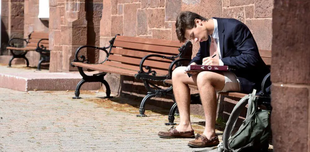 Avon Old Farms student studying outside, sitting on a bench.